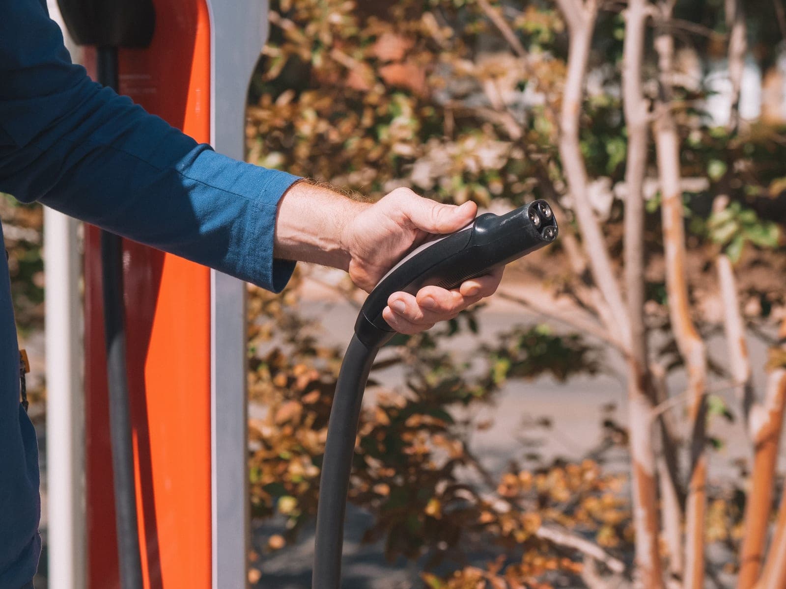 A person holding a Tesla-style charging cable