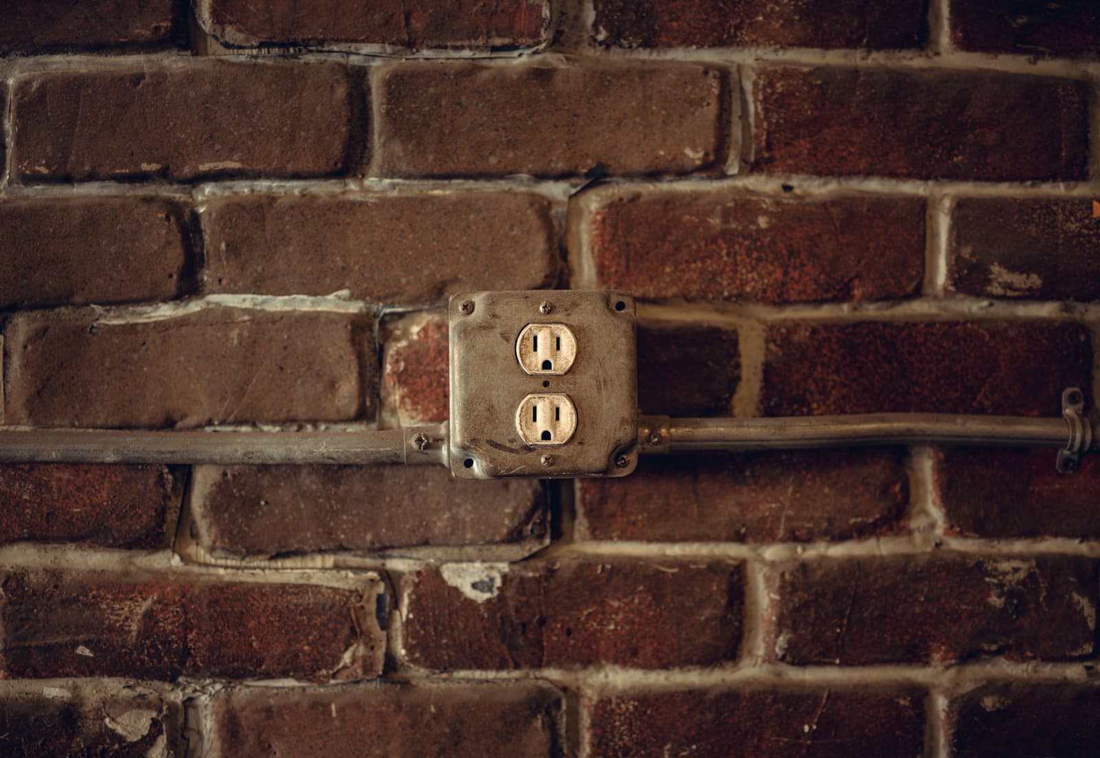 An older style electrical outlet on a wall