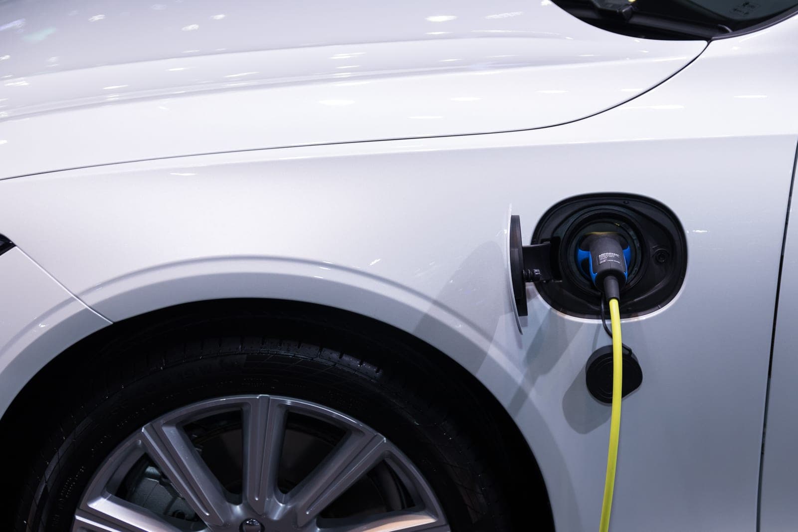 An electric car charging cable plugged in beside a vehicle parked outdoors