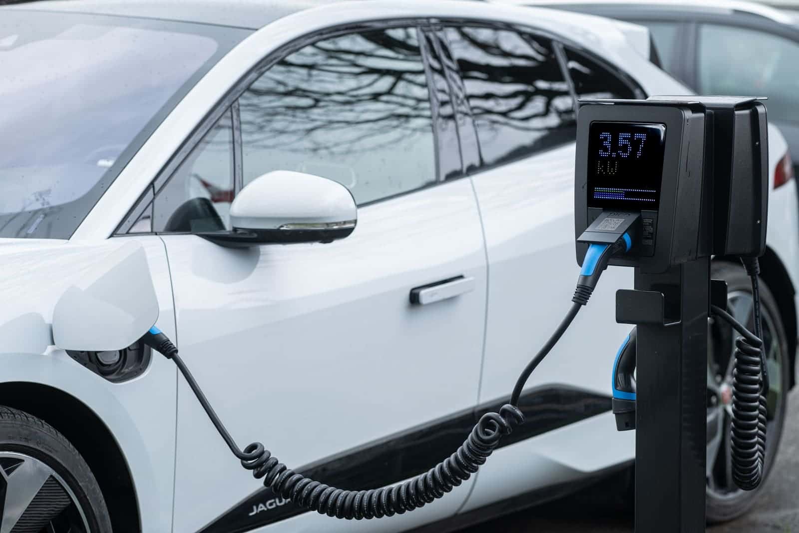 An electric car charging at a unit whose display shows a low kilowatt rate