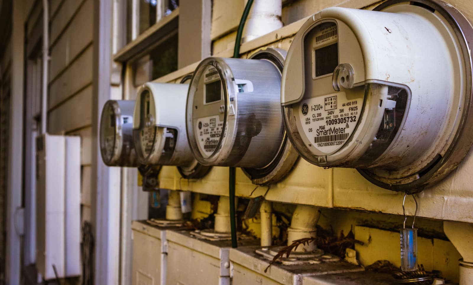 A row of residential electricity meters on the exterior wall of a multi-unit building