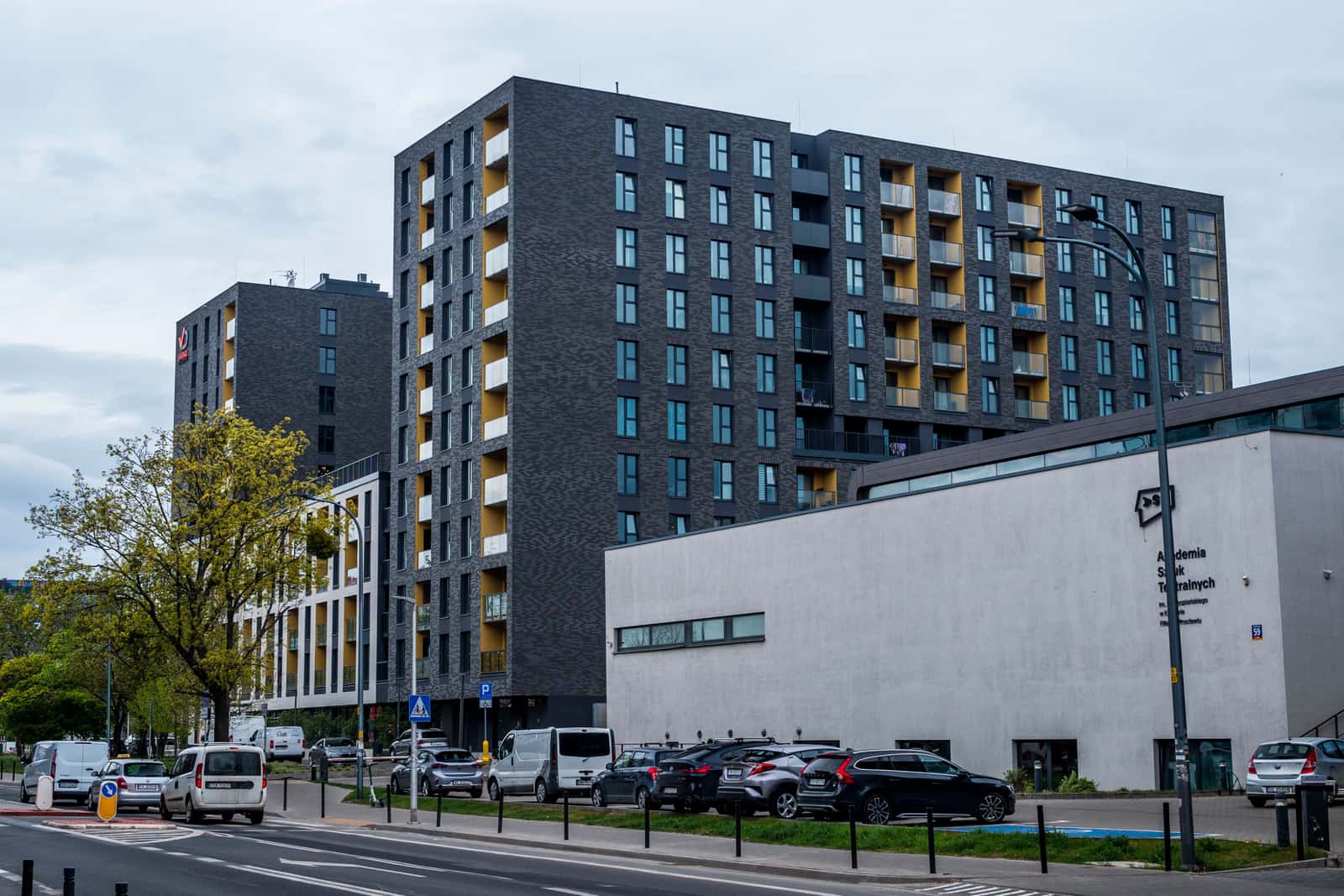 An apartment building exterior with a resident parking area in front