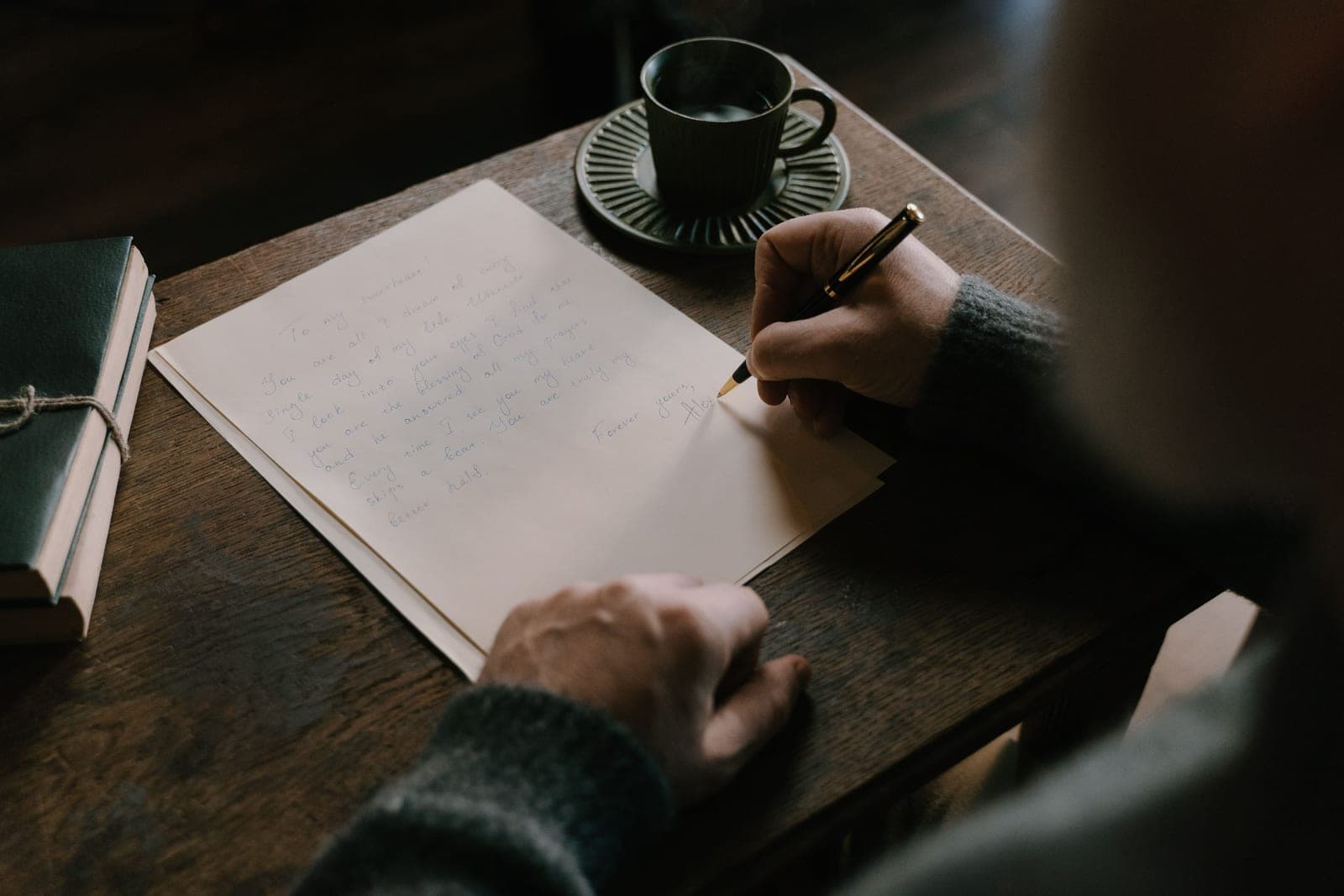 A person writing a letter at a desk