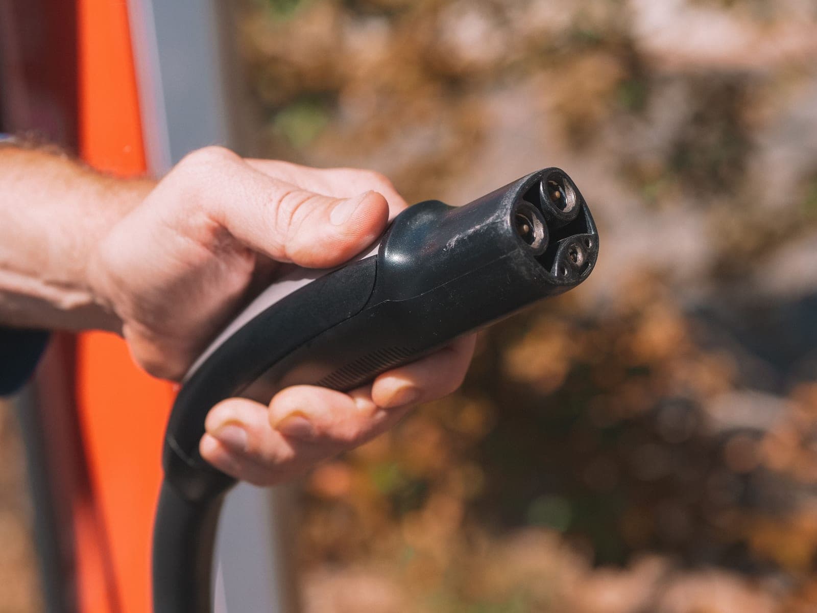 A hand holding an electric vehicle charging plug