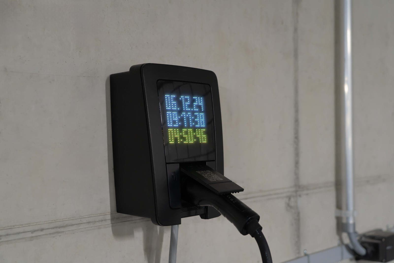 Close-up of an electric car charging station with a digital display showing charge stats