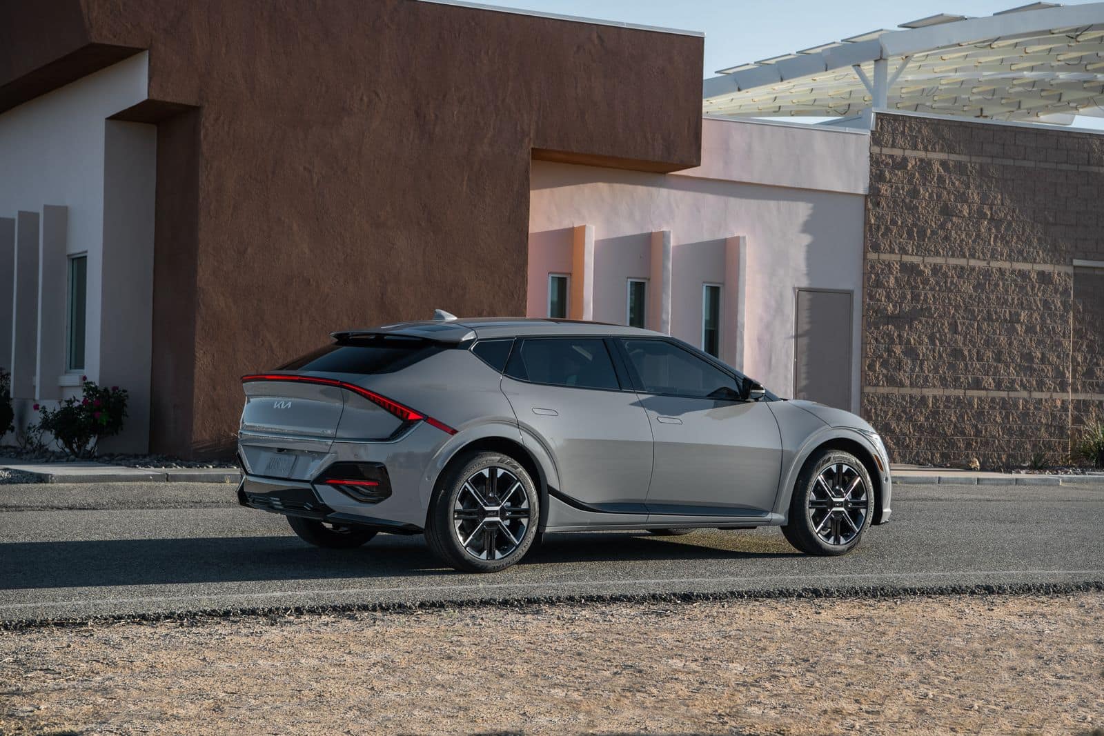 A silver Kia EV6 parked outside a modern building, seen from the rear three-quarter