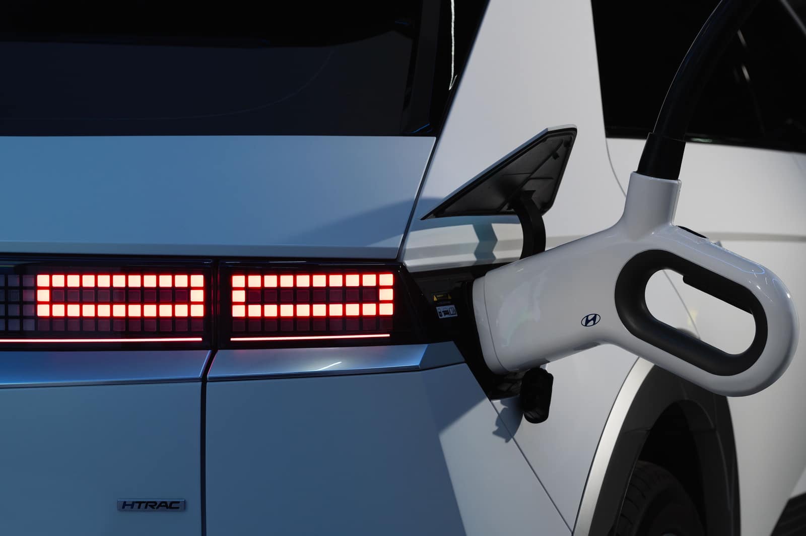A white Hyundai Ioniq 5 plugged in and charging, close-up of the charge port