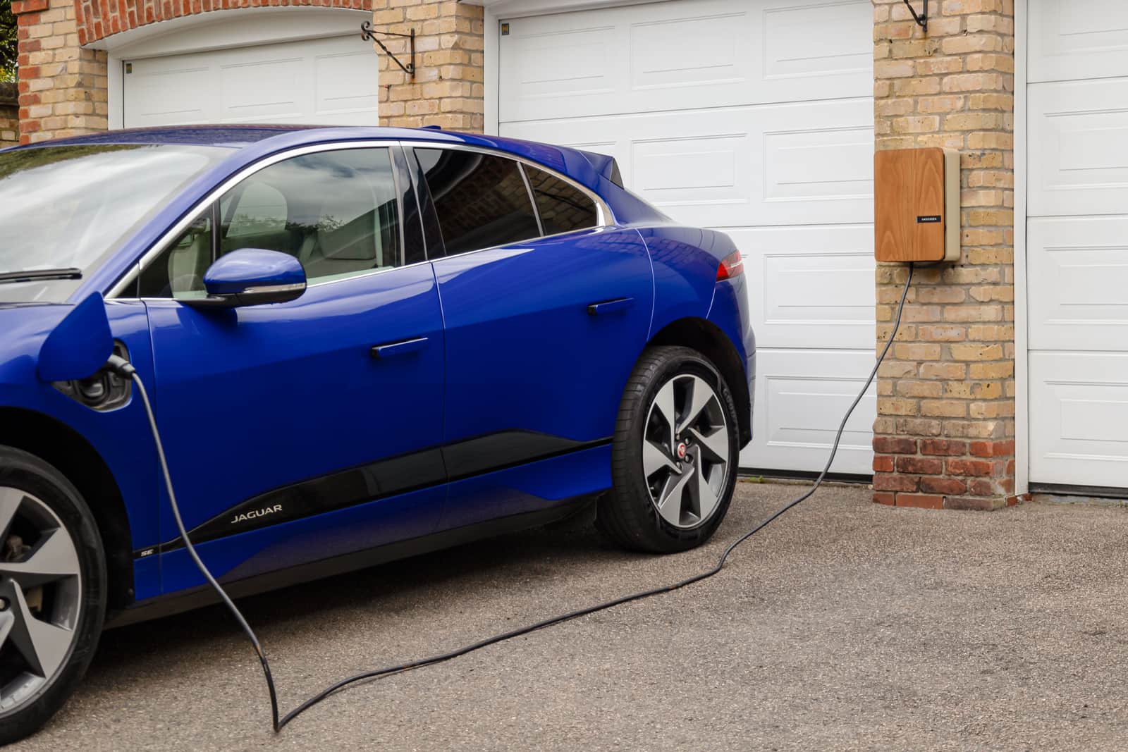 An electric car charging next to a residential building