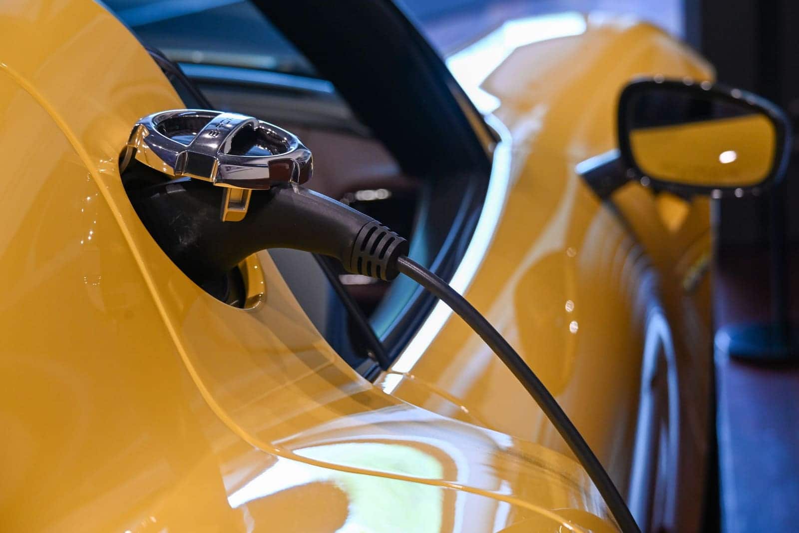 A charging connector plugged into the charge port of a yellow electric car